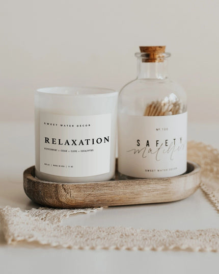 Candle labeled 'Relaxation' and bottle of matches labeled 'Safety Matches' on a wooden tray.