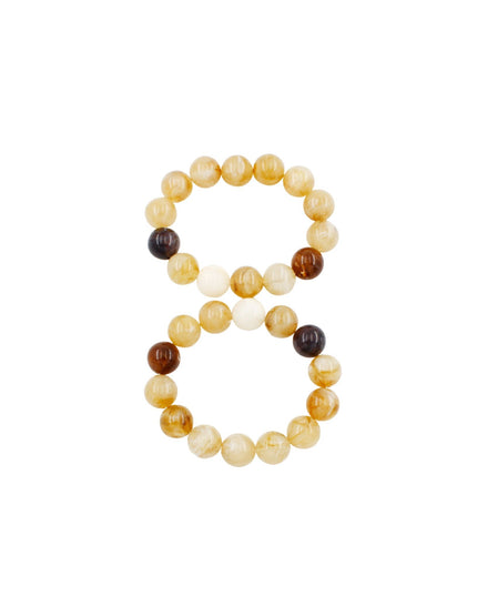 A pair of beaded stretch bracelets arranged to form the number 8, featuring round beads in shades of yellow, cream, and dark brown on a solid white background.