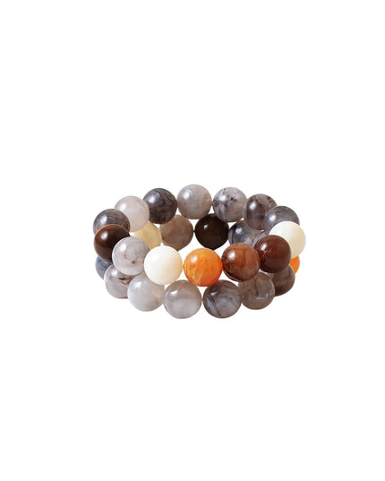 A beaded stretch bracelet made of polished round beads in earthy tones, including brown, gray, white, and a small orange accent bead, shown on a plain white background.