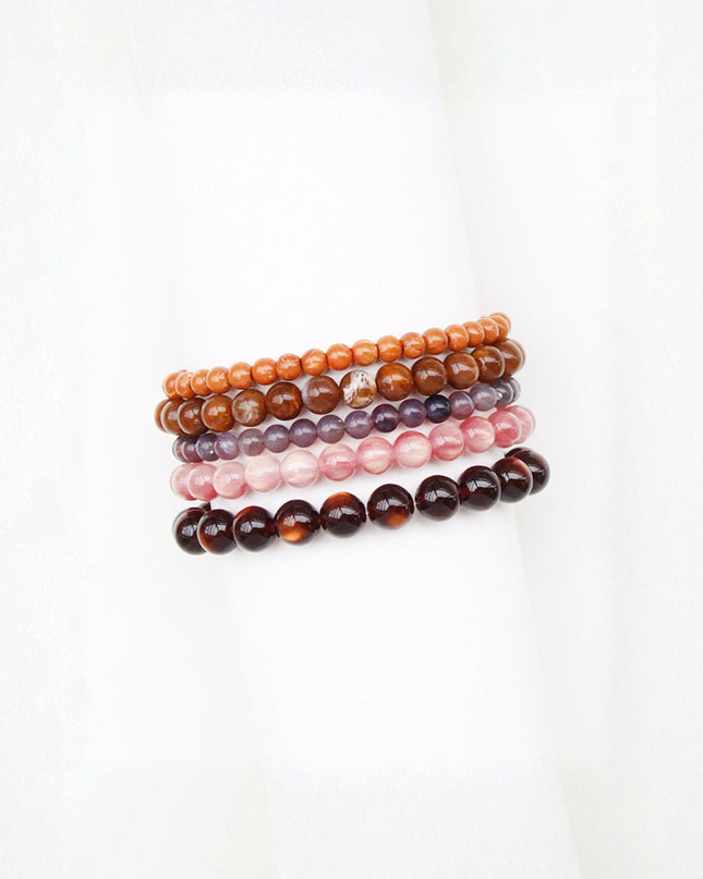 Four beaded stretch bracelets stacked together on a white background, featuring orange, brown, purple, and dark brown tortoiseshell beads.