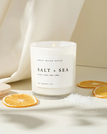 Candle labeled 'Salt + Sea' with orange slices and salt on a neutral background