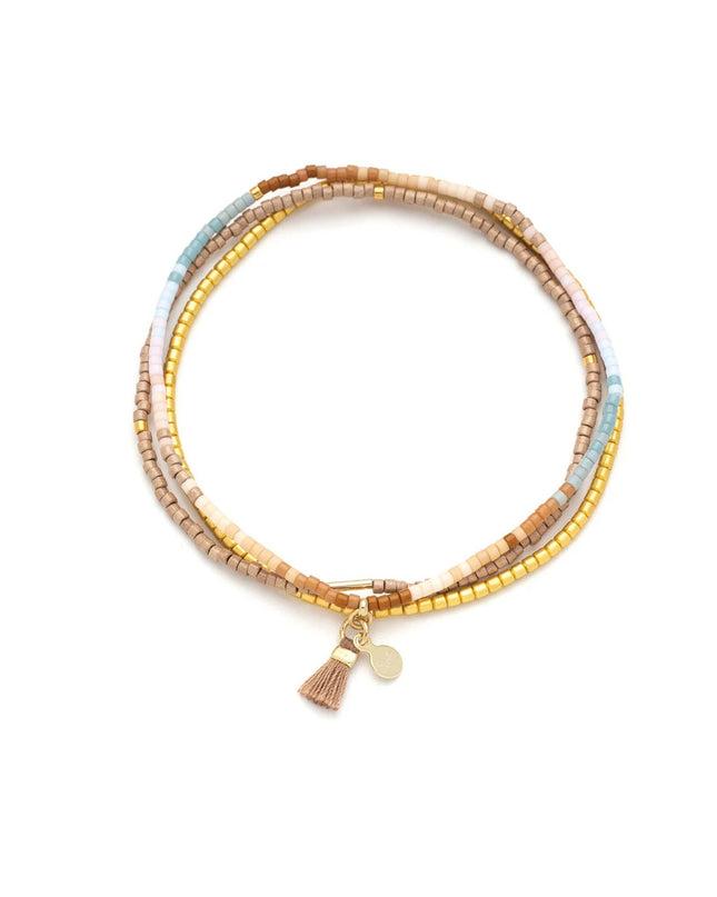 Multicolored beaded bracelet with a tassel charm on a white background