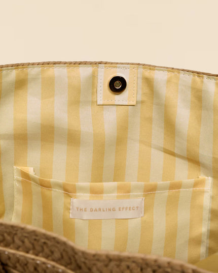 Close-up of a yellow and white striped bag with a brand label on a beige background