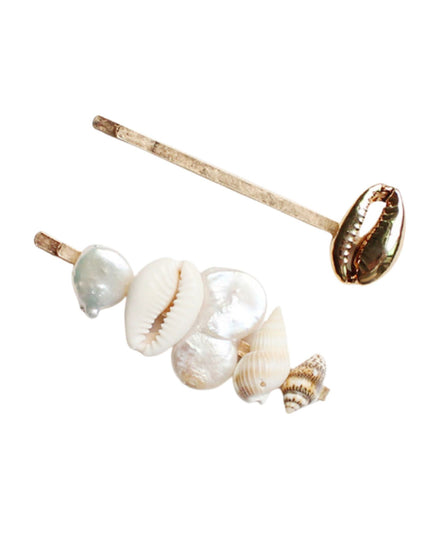 A pair of barrettes with cowrie shells and pearl-like beads on a solid white background.