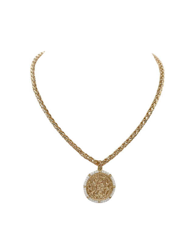 A gold chain necklace with a circular pendant featuring a textured gold center and a border of small clear stones, displayed on a solid white background.