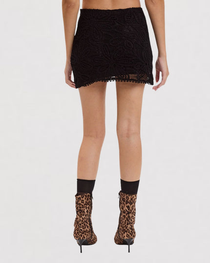 A model shown from the back wearing a black textured mini skirt, black crew socks, and leopard-print ankle boots against a plain white studio background.