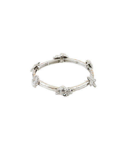 A silver bangle bracelet featuring small starfish and seashell motifs set with clear stones, shown against a plain white background.
