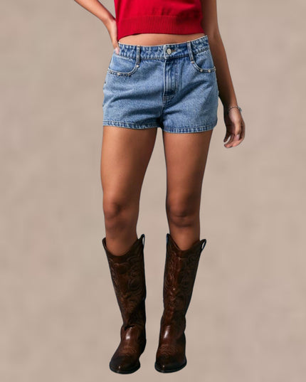 Person wearing denim shorts and brown knee-high boots on a beige background