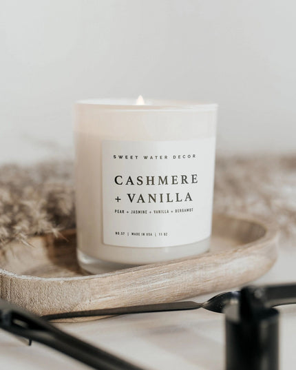 Candle labeled 'Cashmere + Vanilla' on a wooden tray with a neutral background