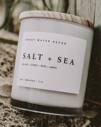 Candle labeled 'Salt + Sea' by Sweet Water Decor on a natural background