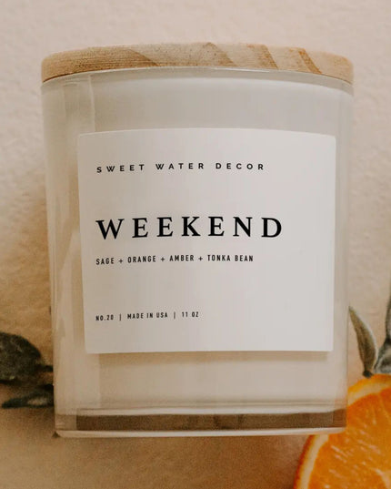Candle with a label reading 'Weekend' by Sweet Water Decor, featuring sage, orange, amber, and tonka bean scents.