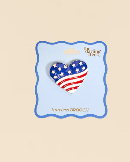 Heart-shaped American flag brooch on a 'The Darling Fleet' card against a beige background