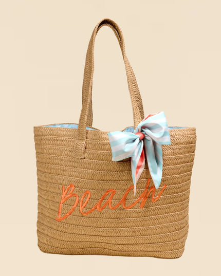 Woven beach bag with 'Beach' embroidery and a ribbon on a beige background