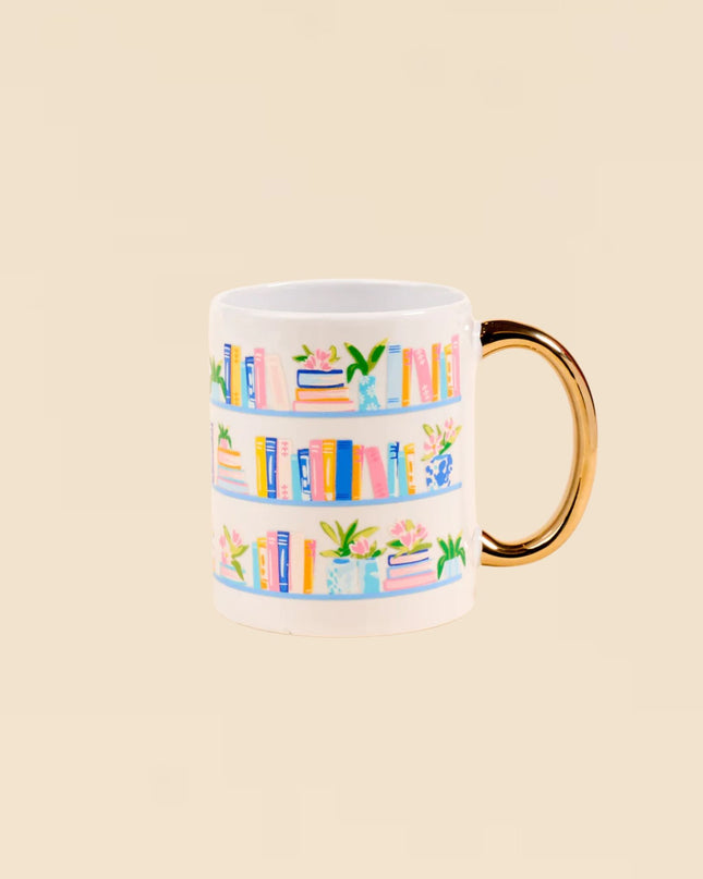 Mug with colorful book design and gold handle on a beige background