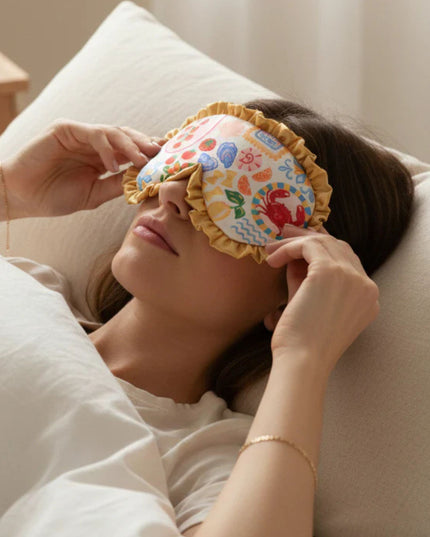 Woman lying on a pillow with a colorful eye mask on her face