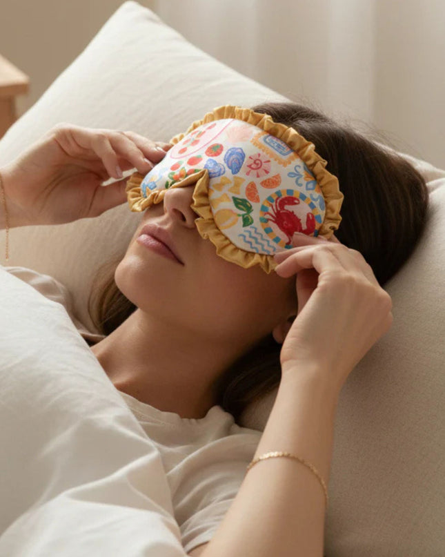 Woman lying on a pillow with a colorful eye mask on her face