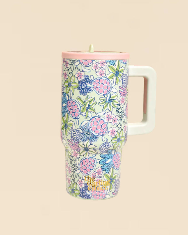 Floral-patterned tumbler with a white handle on a beige background