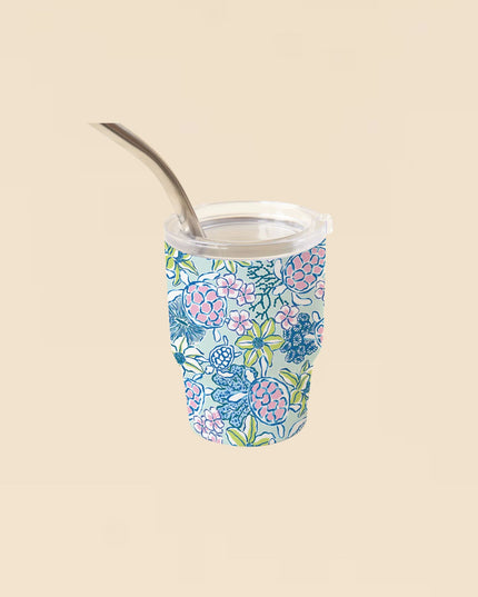 Floral-patterned tumbler with a metal straw on a beige background