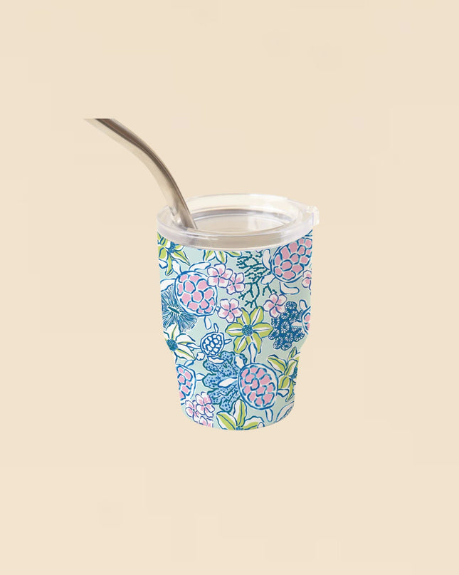 Floral-patterned tumbler with a metal straw on a beige background