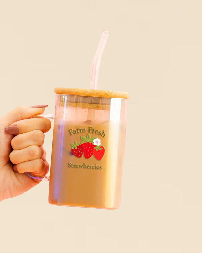 Hand holding a tumbler with 'Farm Fresh Strawberries' design on a beige background
