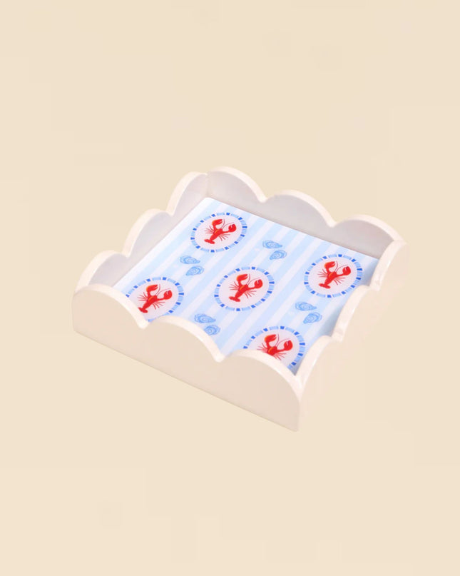 Small white pillow with red lobster pattern on a beige background