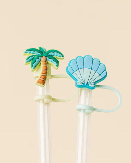 Two straws with tropical-themed ends on a beige background