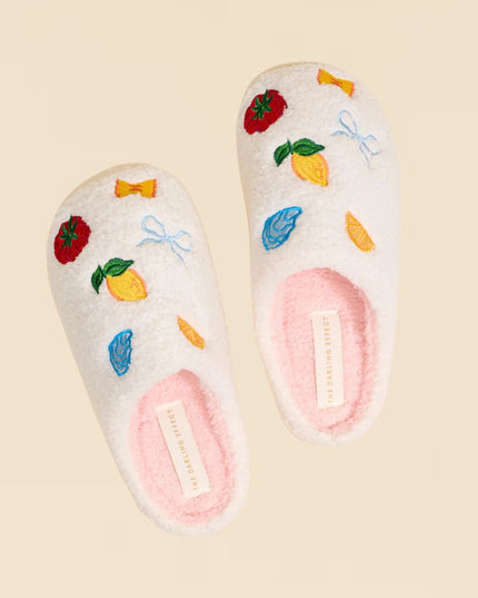 Pair of white slippers with colorful floral designs on a beige background