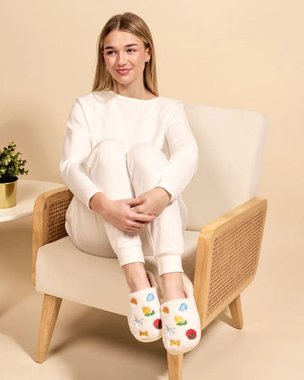 Woman sitting on a chair wearing white pajamas with colorful patterns on her socks.