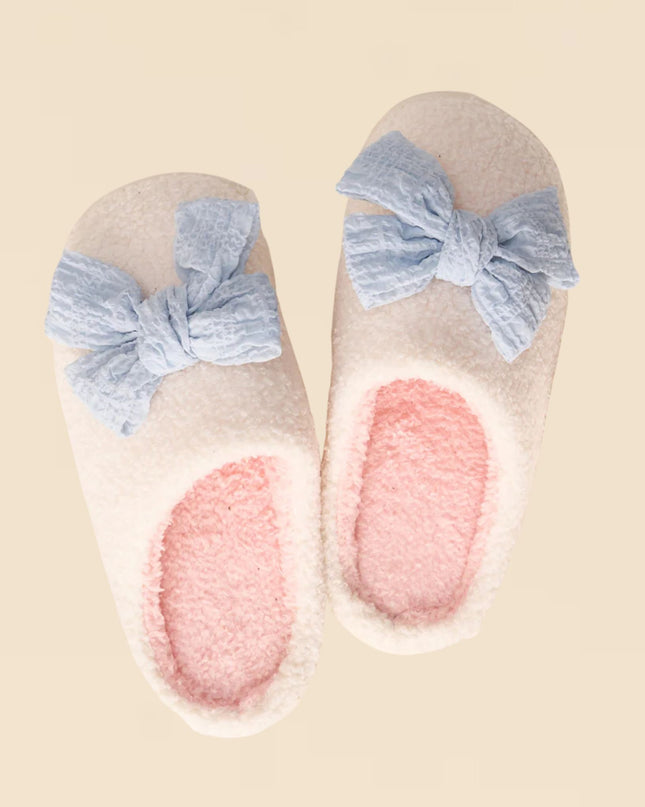 Pair of slippers with blue bow details on a beige background