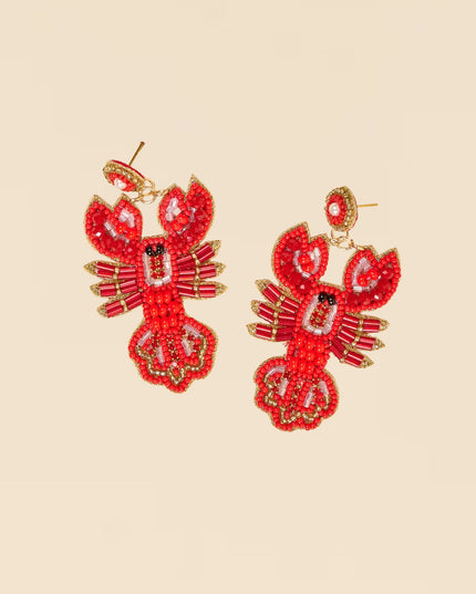 Red beaded lobster earrings on a beige background