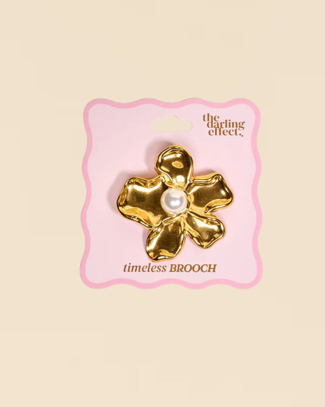 Gold brooch with pearl center on a pink card labeled 'the crafting effect' against a beige background