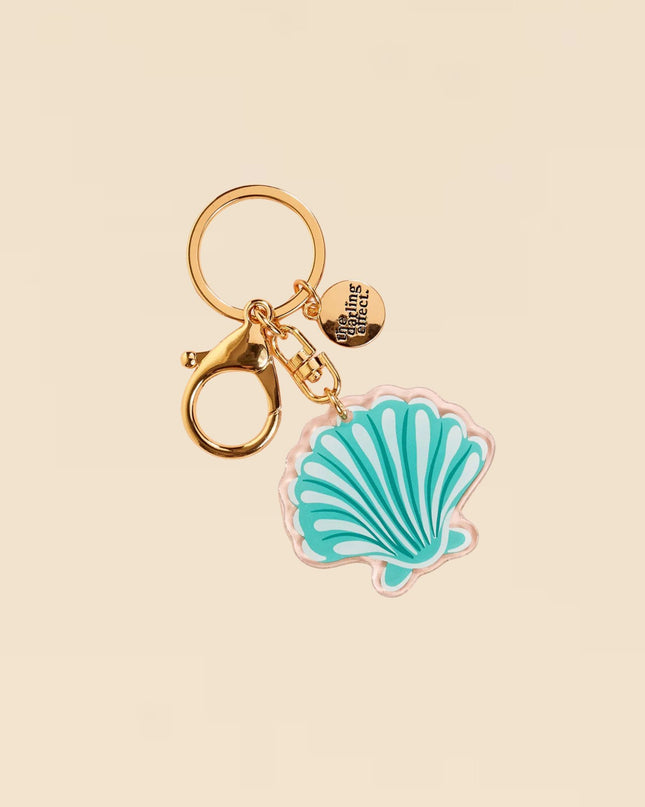 Keychain with a turquoise shell design on a beige background
