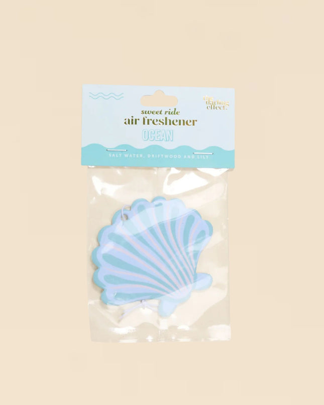 Seashell-shaped air freshener with a label on a beige background