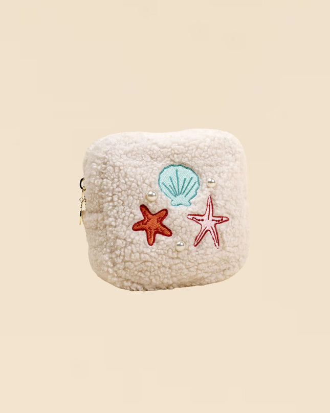Small pouch with starfish and shell decorations on a beige background