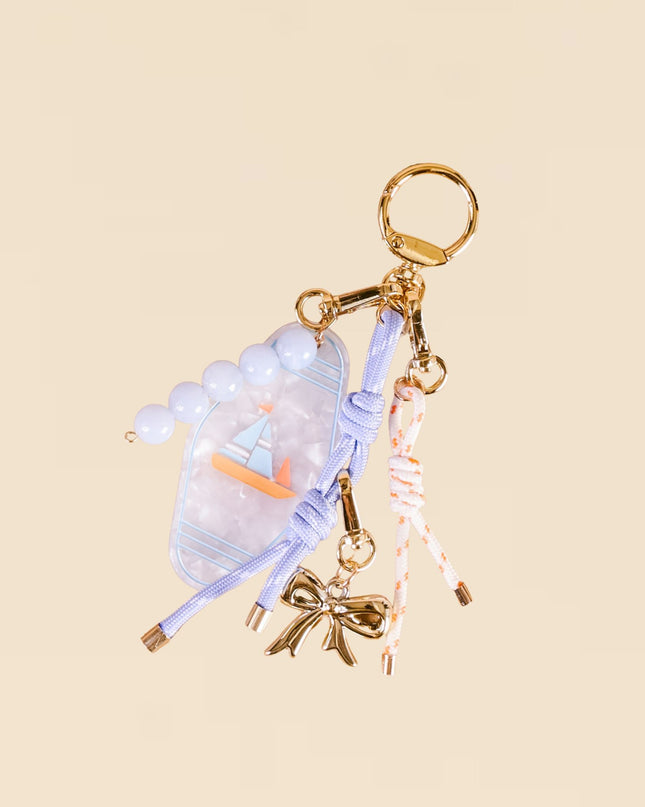 Decorative keychain with a bow and other charms on a beige background
