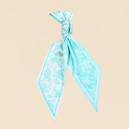 Turquoise floral scarf tied into a knot on a beige background