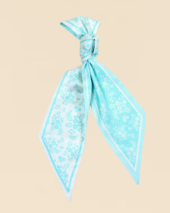 Turquoise floral scarf tied into a knot on a beige background
