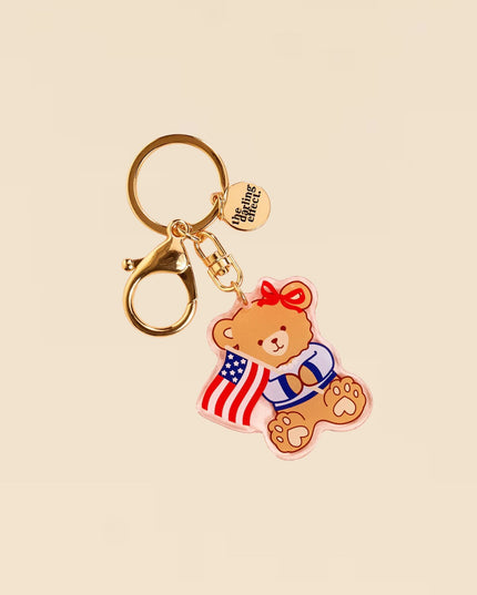 Keychain with bear design holding an American flag on a beige background
