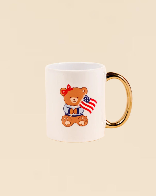 White mug with a teddy bear holding an American flag on a beige background