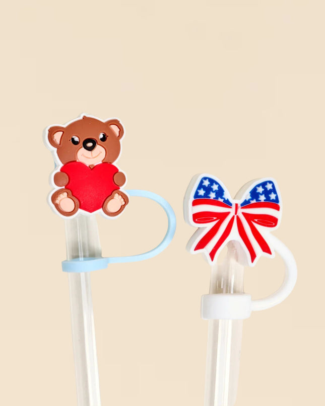 Two decorative items on a beige background: a teddy bear with a red heart and a bow with the American flag design.