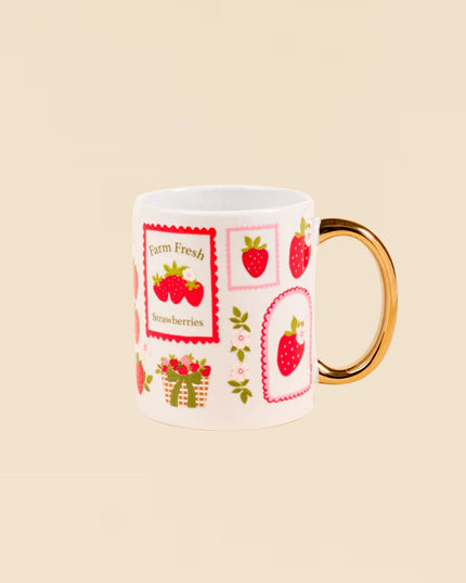 Mug with strawberry design and gold handle on beige background