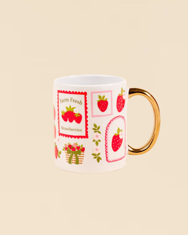 Mug with strawberry design and gold handle on beige background
