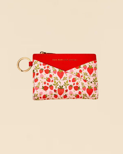Small pouch with strawberry pattern and red top on a beige background