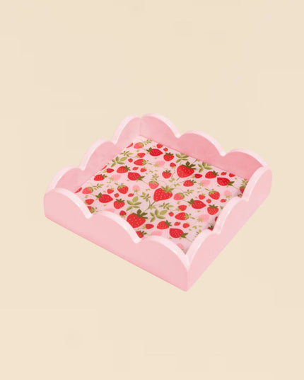 Pink scalloped-edge tray with strawberry pattern on a beige background
