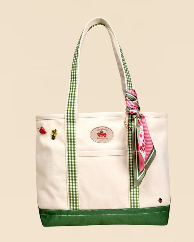 White tote bag with green accents and a pink ribbon on a beige background