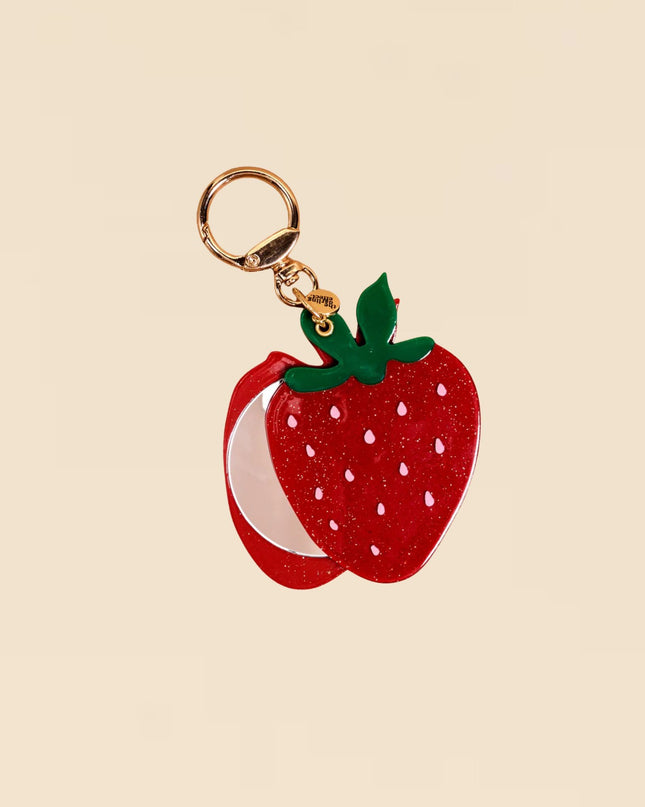 Strawberry-shaped keychain with gold ring on beige background