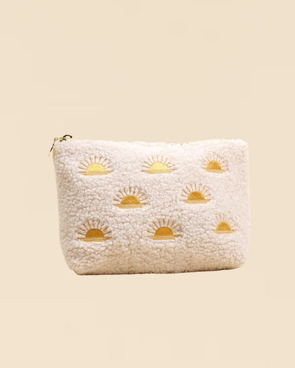 White pouch with gold sun designs on a beige background