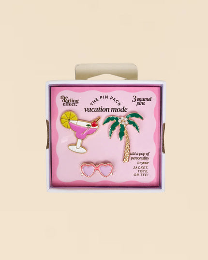 Pack of enamel pins with a palm tree, cocktail, and heart design on a pink background.