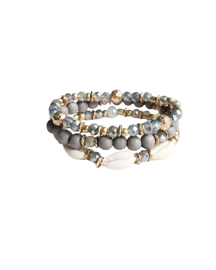 Three beaded stretch bracelets stacked together, featuring gray and white beads with gold-toned spacers and a small white shell accent, on a plain white background.