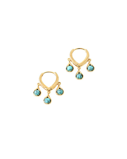 A pair of gold huggie hoop earrings with three small teardrop-shaped turquoise blue gemstones hanging from each earring, set against a plain white background.